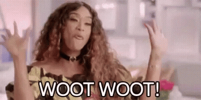 A Woman With Curly Hair Is Sitting On A Couch With Her Hands In The Air . GIF