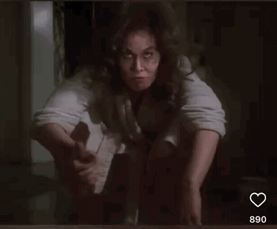 A Woman With Curly Hair Is Sitting On The Floor And Smiling . GIF