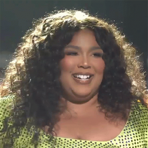 A Woman With Curly Hair Is Smiling And Wearing A Yellow Top With Polka Dots GIF