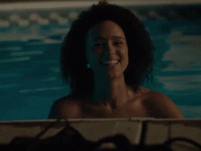 A Woman With Curly Hair Is Smiling In A Pool GIF