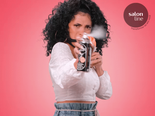 A Woman With Curly Hair Is Spraying A Can Of Salon Line GIF