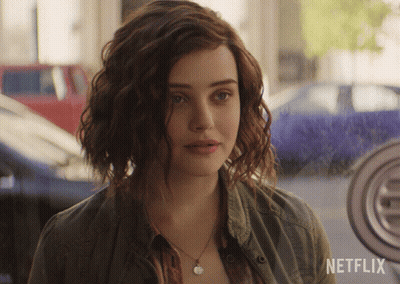 A Woman With Curly Hair Is Standing In Front Of A Netflix Logo GIF