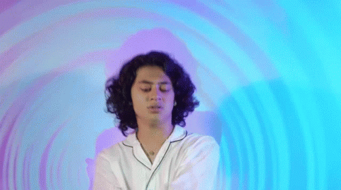 A Woman With Curly Hair Is Standing In Front Of A Purple And Blue Circle . GIF