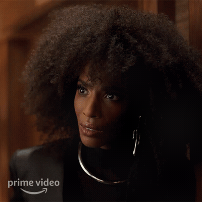 A Woman With Curly Hair Is Standing In Front Of A Sign That Says " Prime Video " GIF