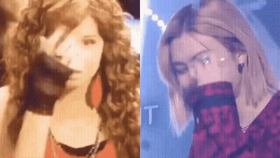 A Woman With Curly Hair Is Standing Next To A Man With Long Hair . GIF