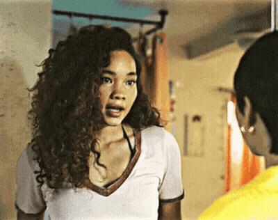 A Woman With Curly Hair Is Standing Next To Another Woman In A Room . GIF