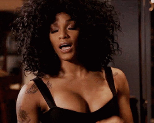 A Woman With Curly Hair Is Wearing A Black Bra And Has A Tattoo On Her Arm . GIF