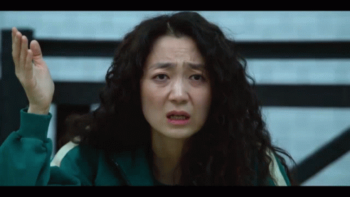 A Woman With Curly Hair Is Wearing A Green Tracksuit And Making A Funny Face GIF
