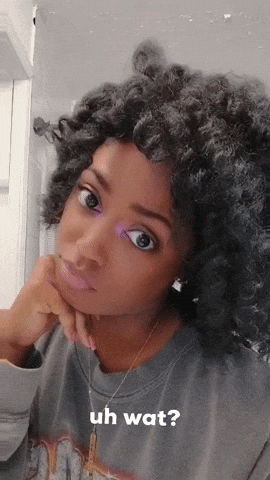 A Woman With Curly Hair Is Wearing A Grey Shirt That Says Uh Wat On It GIF