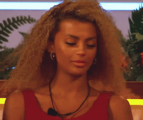 A Woman With Curly Hair Is Wearing A Red Top GIF
