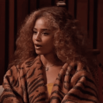 A Woman With Curly Hair Is Wearing A Tiger Print Sweater GIF