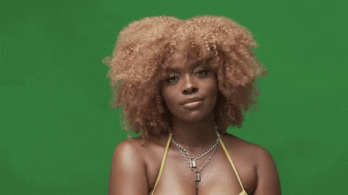 A Woman With Curly Hair Is Wearing A Yellow Bikini Top And A Necklace On A Green Screen . GIF