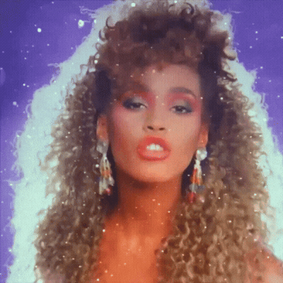 A Woman With Curly Hair Is Wearing Earrings And Red Makeup GIF