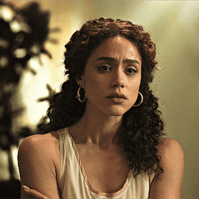 A Woman With Curly Hair Is Wearing Hoop Earrings GIF