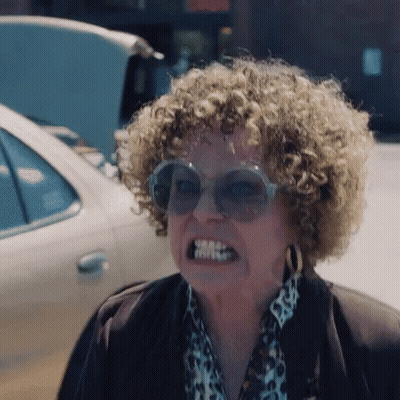 A Woman With Curly Hair Is Wearing Sunglasses And A Leopard Print Shirt . GIF
