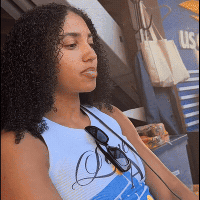 A Woman With Curly Hair Is Wearing Sunglasses And A Shirt That Says Us GIF