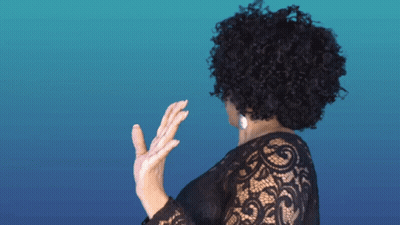 A Woman With Curly Hair Wearing A Black Lace Shirt GIF