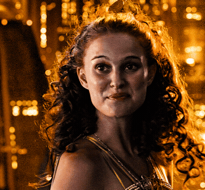 A Woman With Curly Hair Wearing A Crown Looks At The Camera GIF