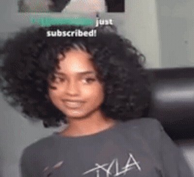 A Woman With Curly Hair Wearing A Gray T-Shirt That Says Kyla GIF