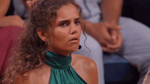 A Woman With Curly Hair Wearing A Green Dress Looks Surprised GIF