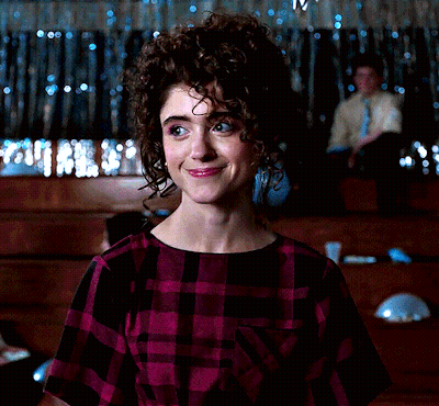 A Woman With Curly Hair Wearing A Purple Plaid Shirt GIF