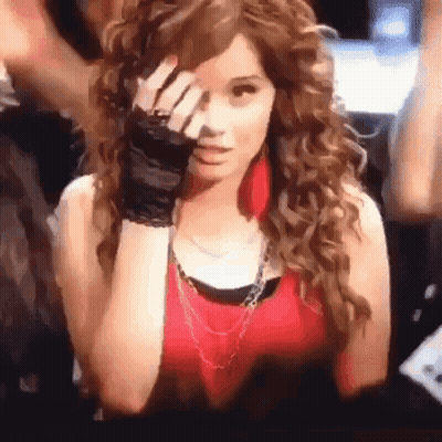 A Woman With Curly Hair Wearing A Red Tank Top And Black Gloves Covering Her Face . GIF