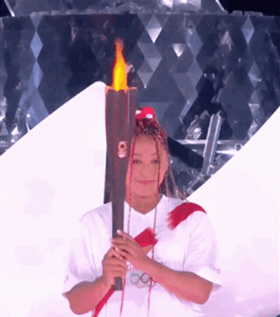 A Woman With Dreadlocks Is Holding A Torch That Says Tokyo On It GIF