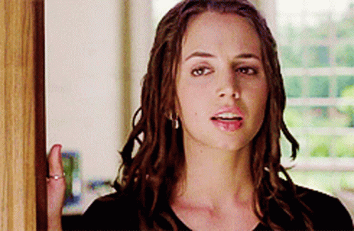 A Woman With Dreadlocks Is Standing In Front Of A Door GIF