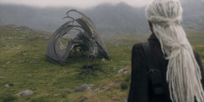 A Woman With Dreadlocks Stands In Front Of A Fallen Dragon GIF