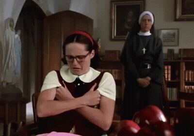 A Woman With Glasses And A Red Headband Is Sitting At A Table With A Nun Standing Behind Her GIF