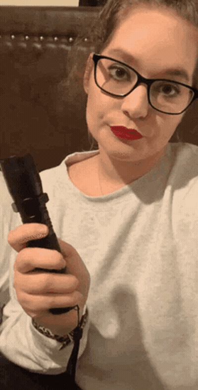 A Woman With Glasses And Red Lipstick Is Holding A Flashlight GIF