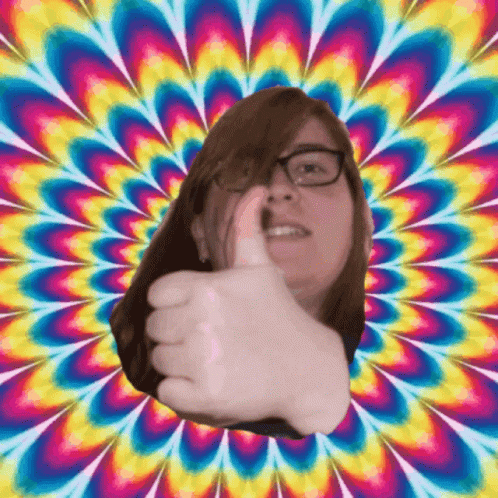 A Woman With Glasses Giving A Thumbs Up In Front Of A Colorful Background GIF