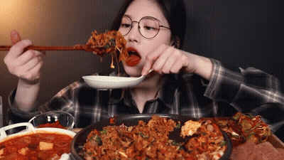 A Woman With Glasses Is Eating Food With Chopsticks GIF