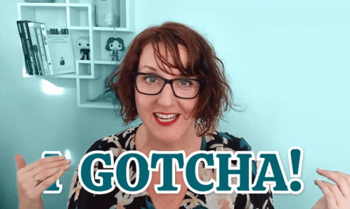 A Woman With Glasses Is Holding A Piece Of Paper That Says " Gotcha " GIF