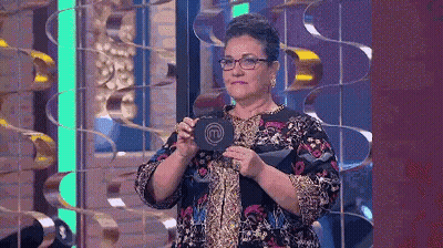 A Woman With Glasses Is Holding A Sign That Says M On It GIF