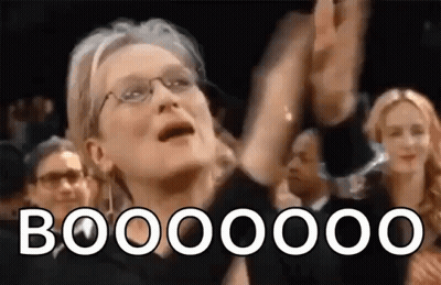 A Woman With Glasses Is Raising Her Hands In The Air While A Crowd Applauds Her . GIF
