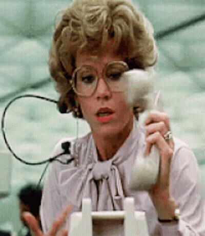 A Woman With Glasses Is Talking On A Telephone GIF