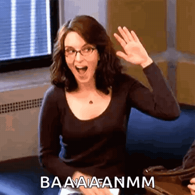 A Woman With Glasses Is Waving Her Hand And The Words Baaaaanmm Are Above Her GIF