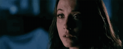 A Woman With Glowing Eyes Is Looking At The Camera In A Dark Room . GIF