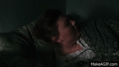 A Woman With Glowing Eyes Is Sitting Next To A Lamp On A Table GIF