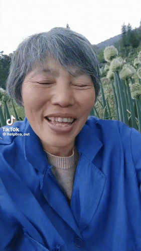 A Woman With Gray Hair And A Blue Jacket Has A Tiktok Watermark On Her Face GIF
