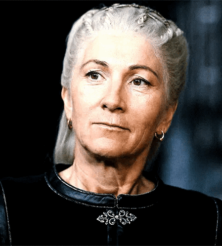 A Woman With Gray Hair Is Wearing Earrings And A Black Top GIF