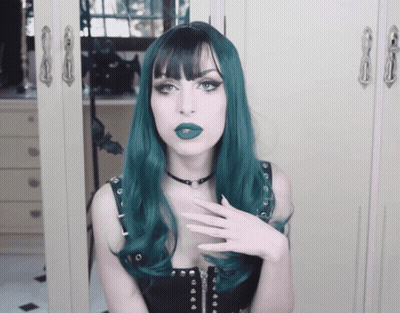 A Woman With Green Hair And A Black Choker Looks At The Camera GIF