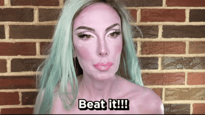 A Woman With Green Hair And White Paint On Her Face Says " Beat It " GIF