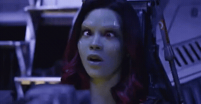 A Woman With Green Hair Is Sitting In A Chair With Her Mouth Open And A Surprised Look On Her Face . GIF