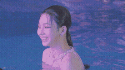 A Woman With Green Hair Is Swimming In A Pool And Smiling . GIF