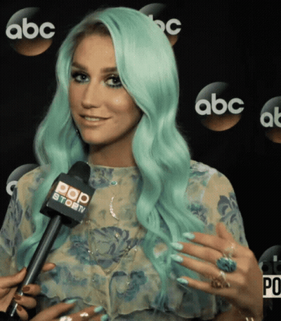 A Woman With Green Hair Is Talking Into A Microphone That Says Pop Story GIF