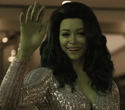 A Woman With Green Hair Is Waving Her Hand And Smiling GIF