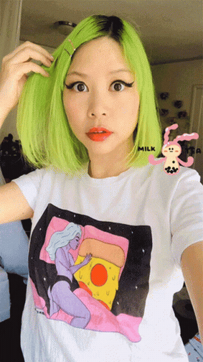 A Woman With Green Hair Is Wearing A T-Shirt With A Picture Of A Woman And A Pizza On It GIF