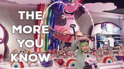 A Woman With Green Hair Stands In Front Of A Display Of Candy And A Sign That Says " The More You Know " GIF